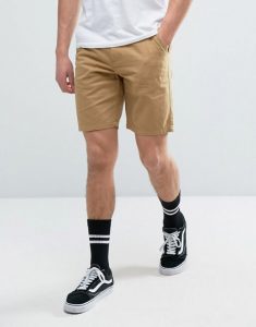 Beige Thigh Level Shorts Along With Black Sneakers